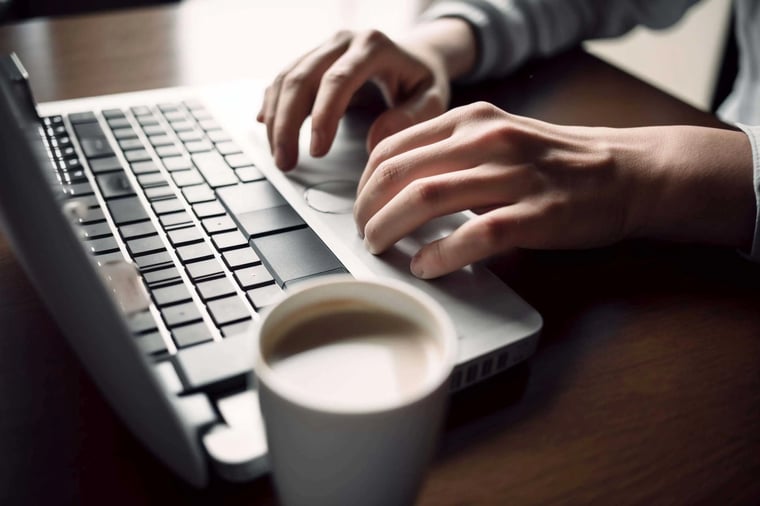 A close-up of a persons hands typing on a keyboard with  (2)