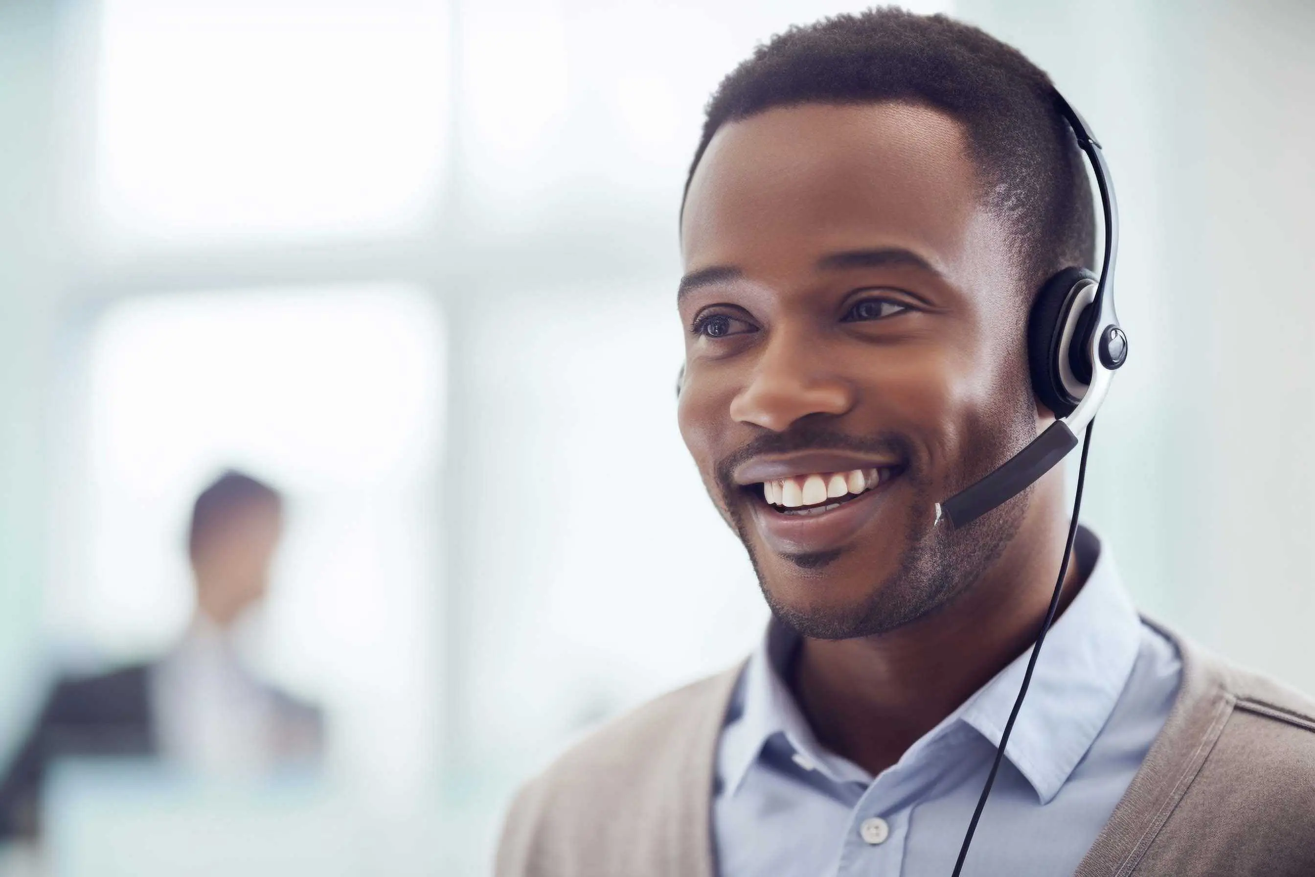 A salesperson with a headset smiling as they talk to a p (2)